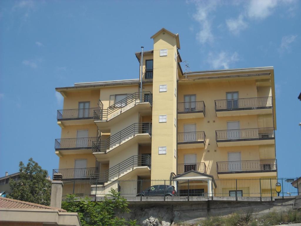 拉戈內格羅的住宿－Hotel Caimo Bed-Breakfast，带阳台的黄色建筑,前面有汽车