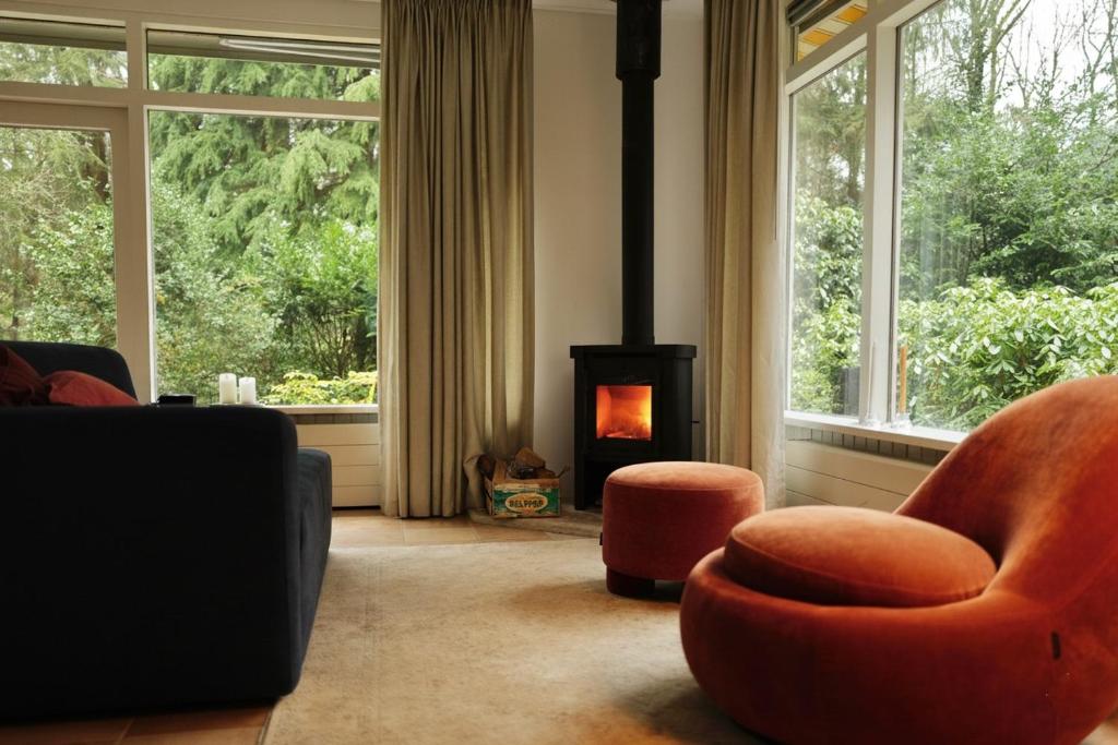 sala de estar con silla naranja y chimenea en Cozy forest house ideal for relaxing, en Wateren