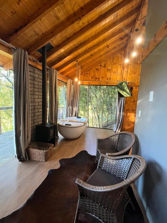 a room with a tub and chairs in a cabin at Chalé Refúgio Panorâmico in Canela