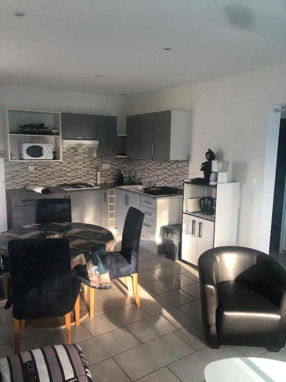 a living room with a table and chairs and a kitchen at petite maison calme in Hourtin