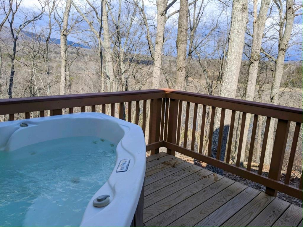 a hot tub on a wooden deck with trees at Eaglet Cabin near the Shenandoah River in Oak Hill