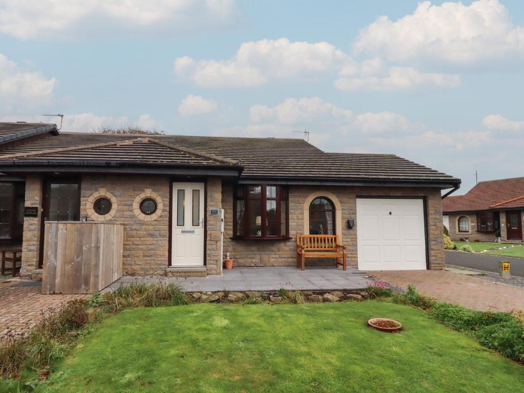 a brick house with a bench in the front yard at Nobles Nook in Seahouses