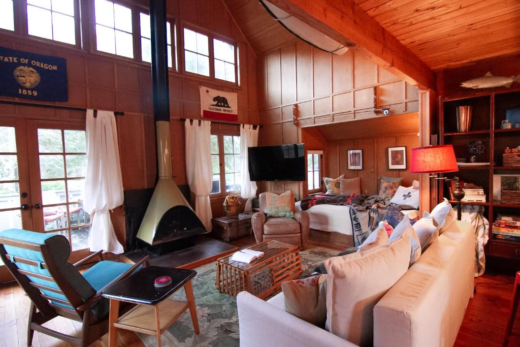 a living room with couches and a tv and windows at Cute Cabin in Yachats! Short walk to rivers' edge! River Walk Cabin in Yachats