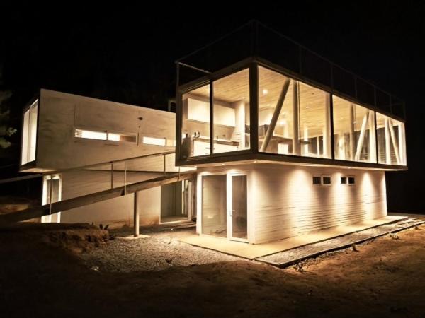 トゥンケンにあるConcrete house overlooking the ocean and beach accessの夜間のライトアップファサード付きの大きな建物