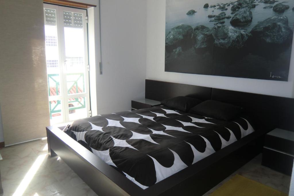 a black and white bed in a room with a large screen at Apartamento Santa Cruz in Santa Cruz