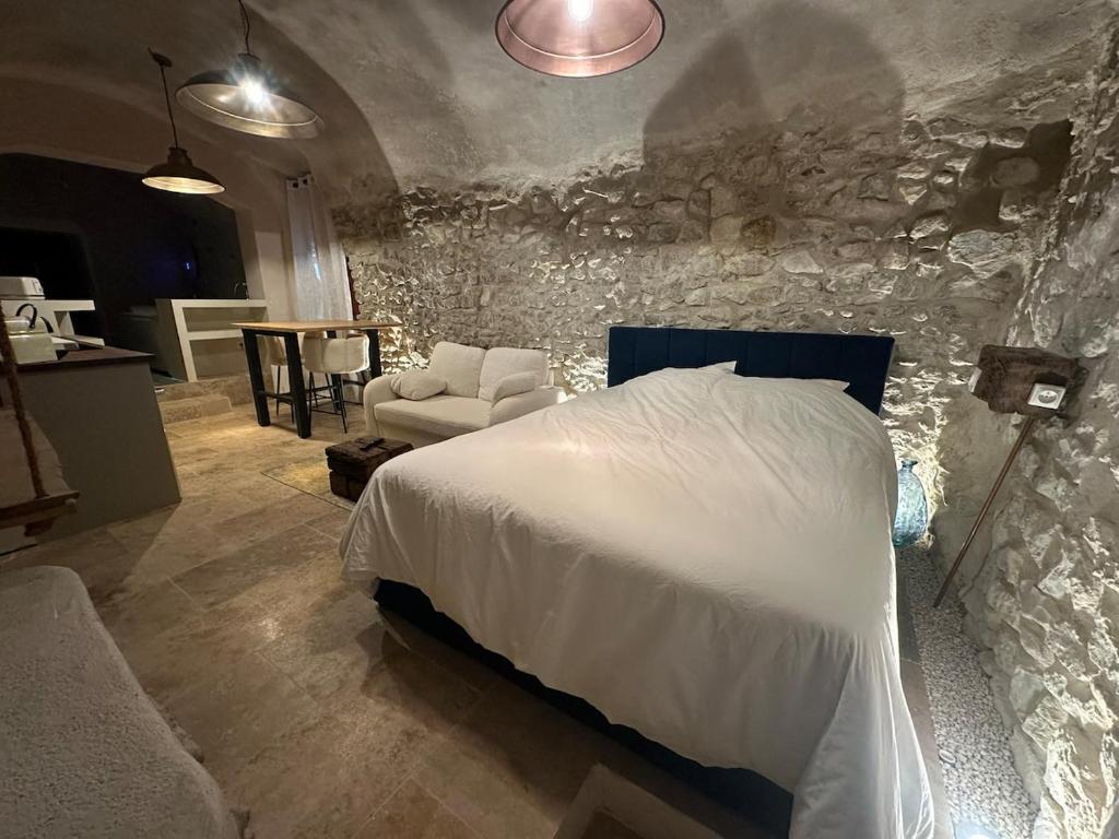 a bedroom with a bed and a stone wall at Suite secrète avec jacuzzi ambiance romantique in Livron-sur-Drôme