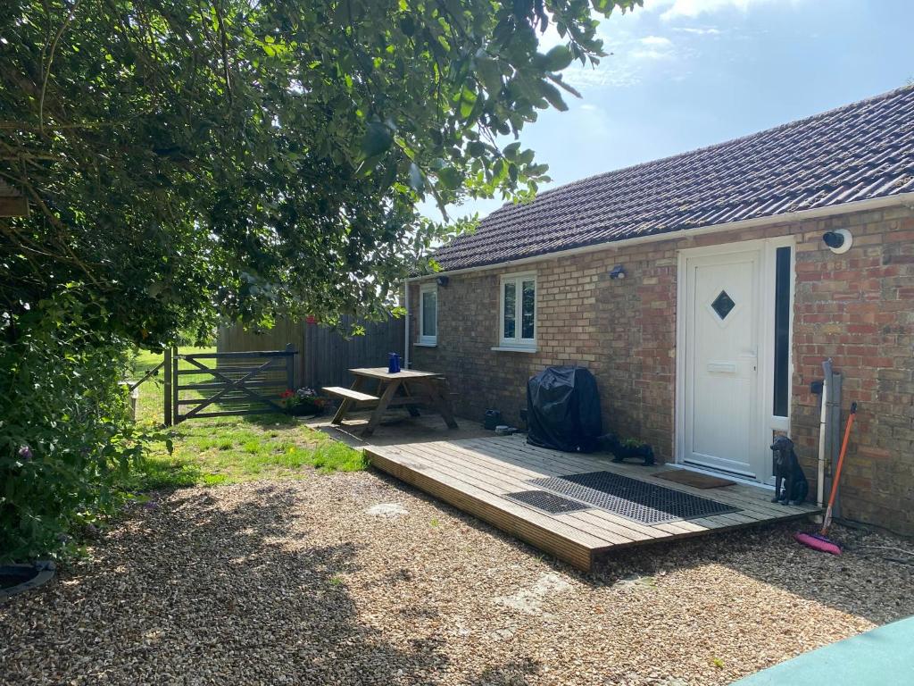 a wooden deck next to a brick building with a white door at Little Owls Nest Holiday Home in Wisbech