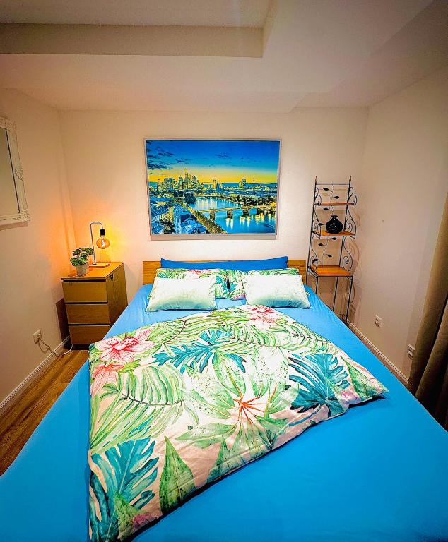 a bedroom with a blue bed with a painting on the wall at Skylineblick Doppelzimmer in einer 2 Zimmer-Ferienwohnung mit Gemeinschaftsbereichen wie Wohn-Küchenbereich sowie Bad und WC in Seligenstadt