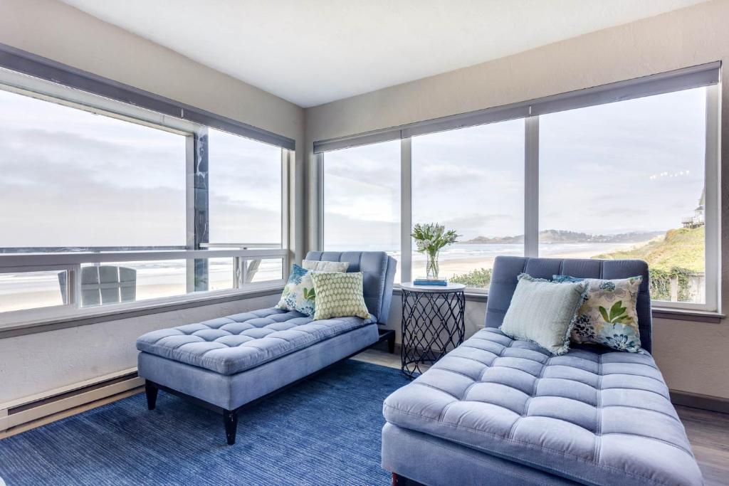a living room with a couch and large windows at Ocean Front Condo, View of Lighthouse, Nye Beach! Nye Beacon in Newport
