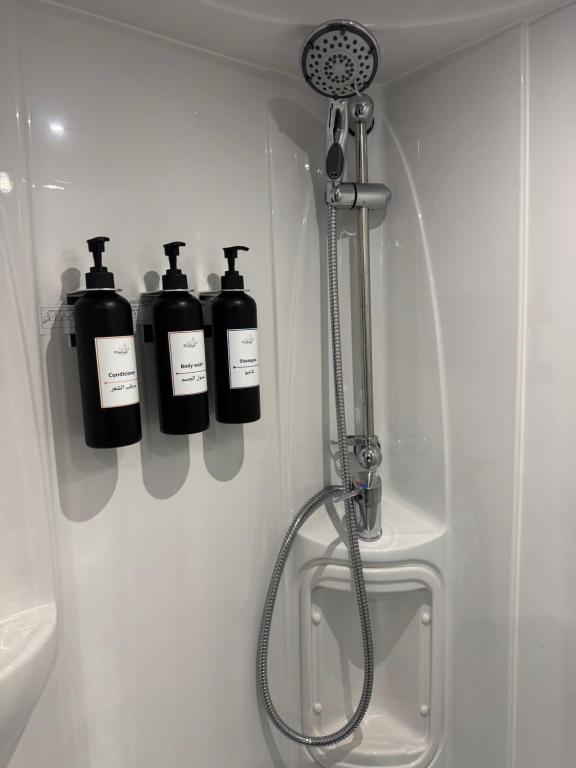 a bathroom with four bottles of soap and a shower at Flamingo Caravan in Ash Shāb