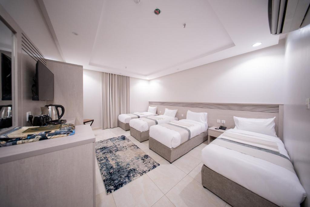 Una habitación de hotel con tres camas y un televisor. en Orvana Al Naseem Hotel, en La Meca