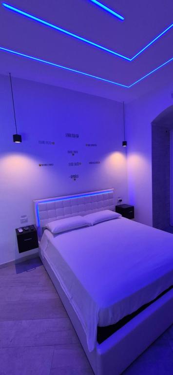 a bedroom with a large white bed with purple lights at Costantinopoli Suite in Giovinazzo