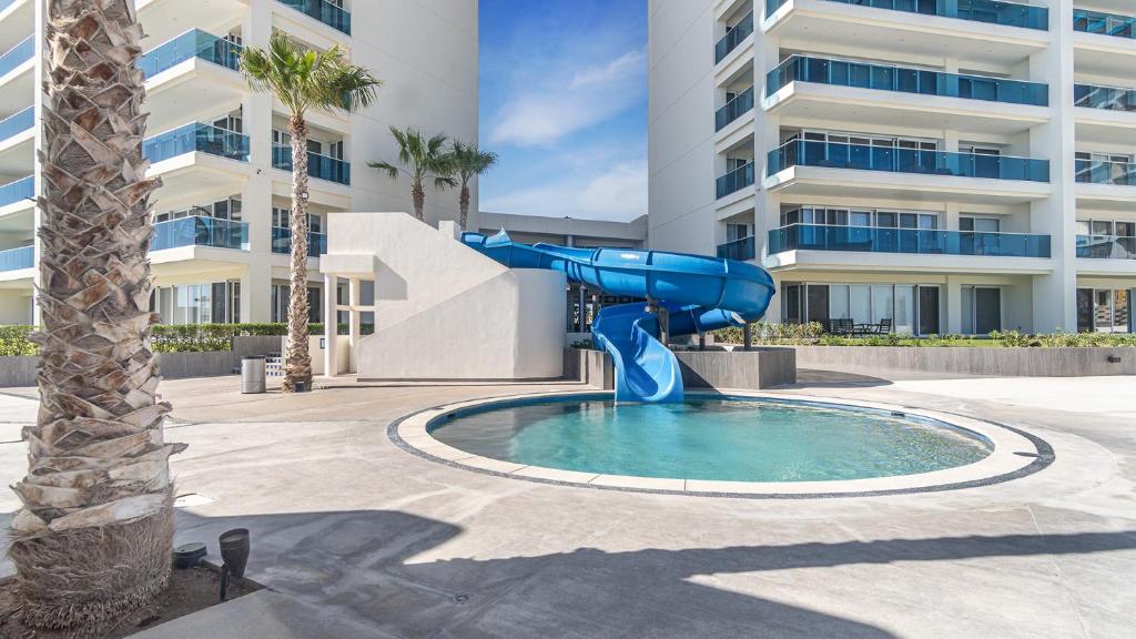 a slide in a pool in front of a building at Encantame Towers Velero 901 in Playa Encanto