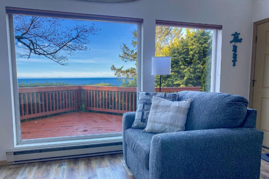 a blue couch in a living room with a large window at Ocean View in Yachats! Dog Friendly! Ya-Hut in Yachats