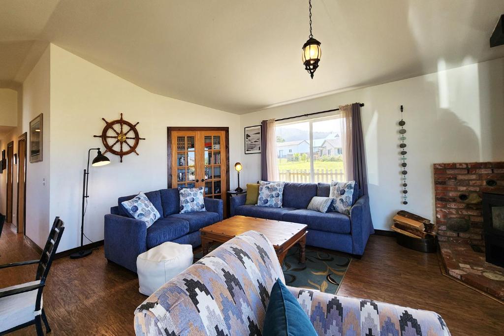 a living room with blue couches and a table at Ocean View, Walk to Everything! Dog Friendly! Wheelhouse Cottage in Yachats