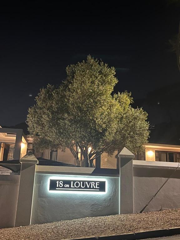 a sign that reads lounge in front of a tree at 18 On Louvre Guesthouse in Paarl
