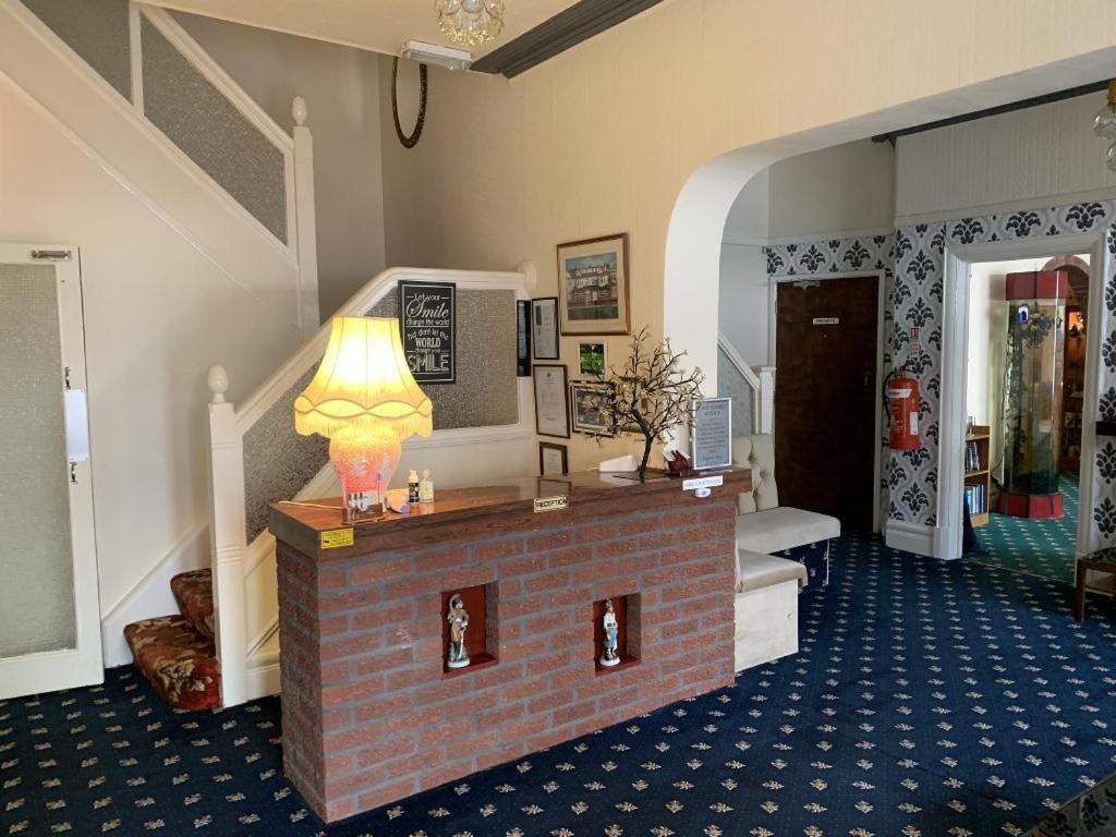 a room with a brick fireplace with a lamp on it at Bramleigh Hotel in Blackpool