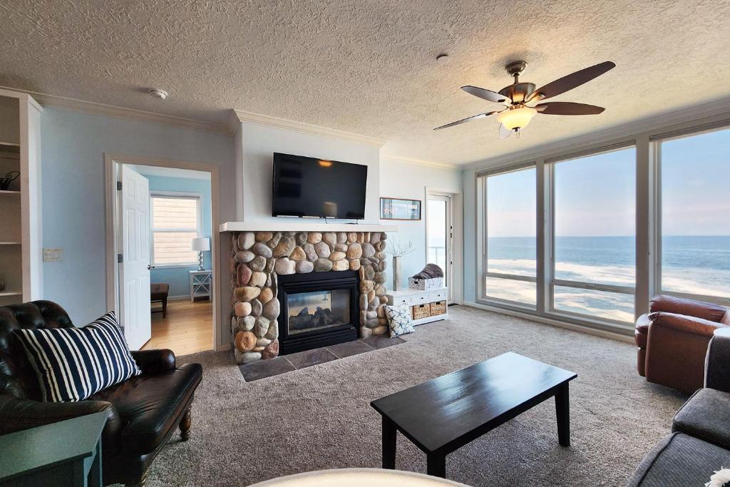 a living room with a fireplace with a view of the ocean at Spectacular Ocean Front Condo with Community Club House & Pool! Whale Crossing in Depoe Bay