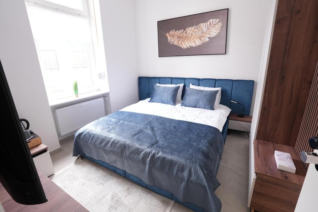 a bedroom with a blue and white bed and a window at Luxury Apartments - Wohnung IA - Elegante Mini-Suite I Stock in Neuwied