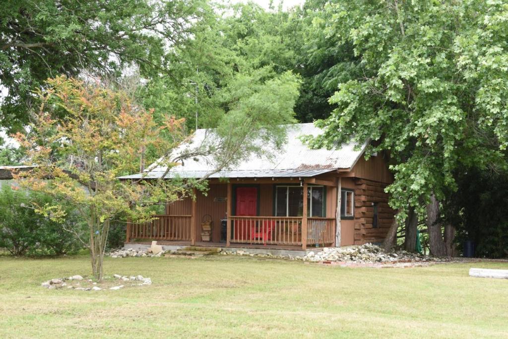 a wooden house with a red door in a yard at Jones Riverside Cabin in Utopia