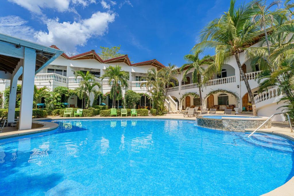 una piscina frente a un edificio con palmeras en Hotel Mar Rey, en Tamarindo