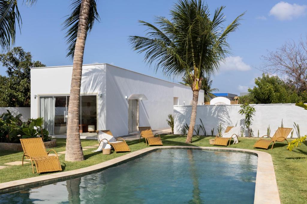 サン・ミゲル・ド・ゴストーゾにあるPousada Vila Nazareの家の前のヤシの木と椅子付きのプール