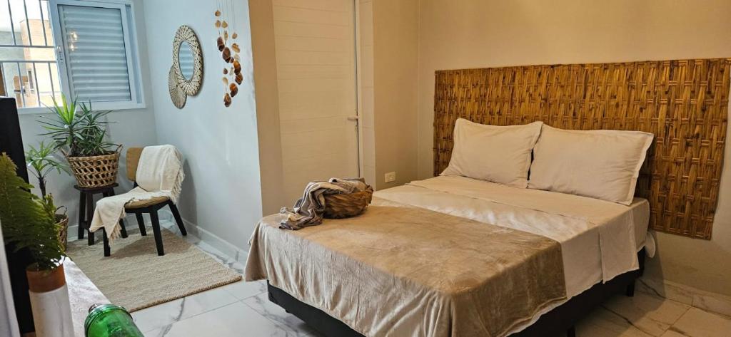 a bedroom with a bed with a wooden headboard at Pousada Coisa Nossa in Itanhaém