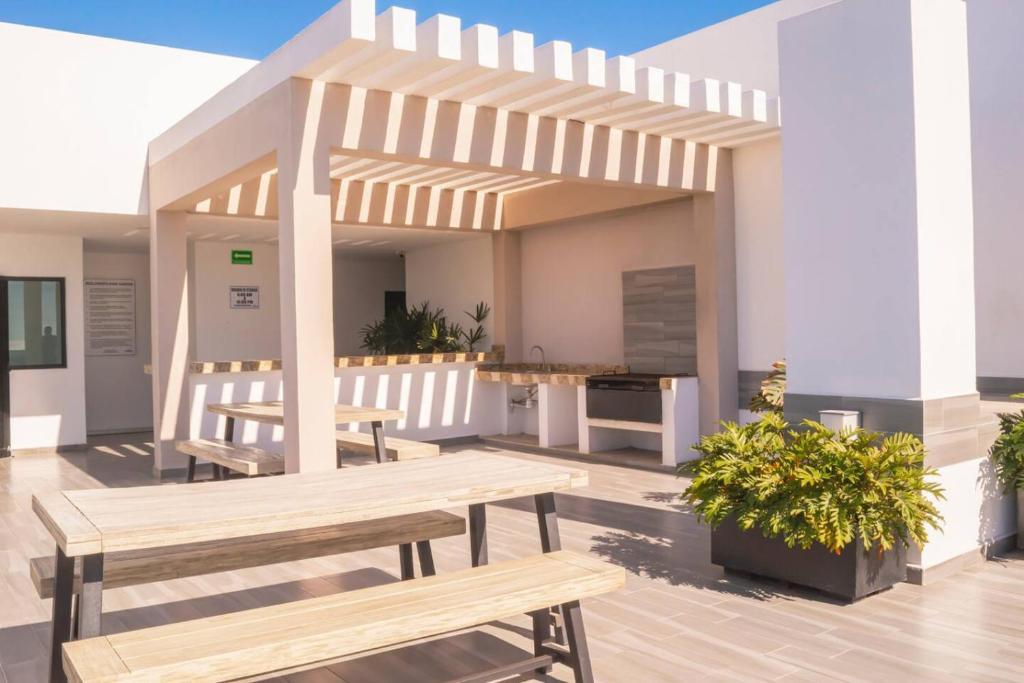 a patio with wooden benches and a pergola at Alojamiento A Unas Calles del Malecon in Mazatlán