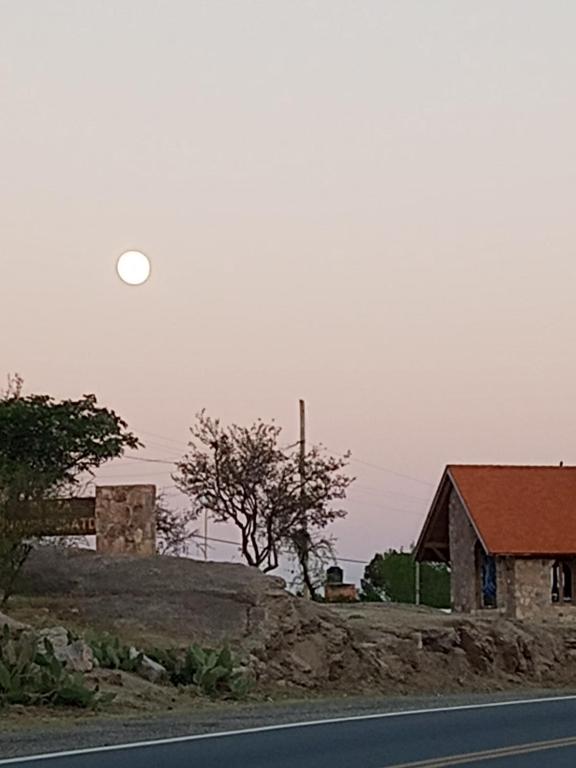 een maan die opkomt boven een huis en een weg bij Los patos in Capilla del Monte