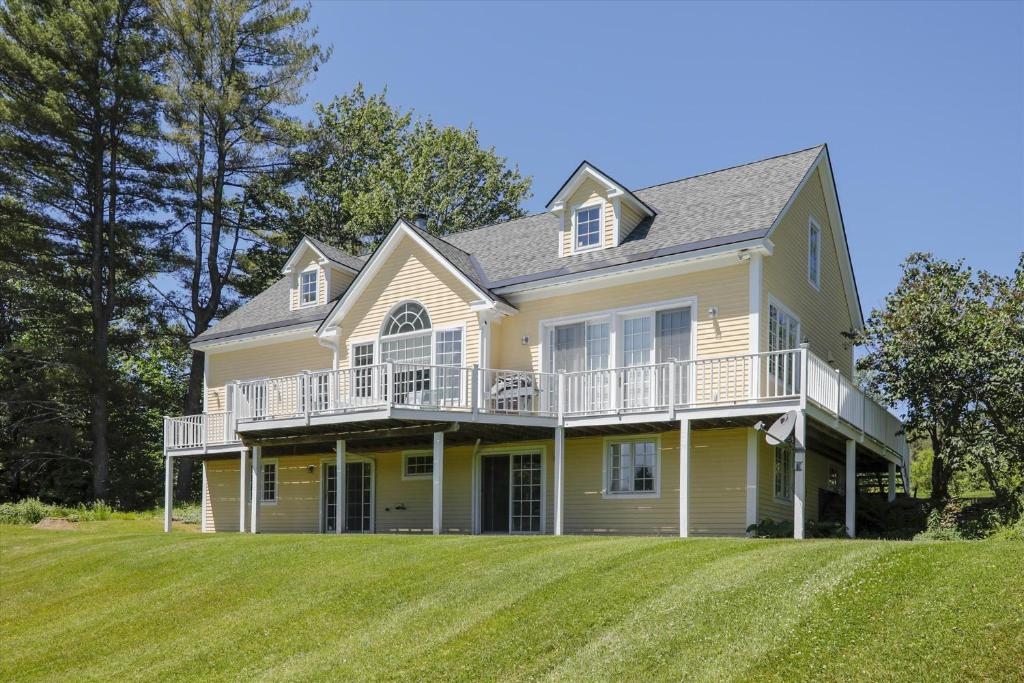 a large yellow house with a large yard at Weeks Hill: 5 br, fireplace, a/c, deck, views! in Stowe