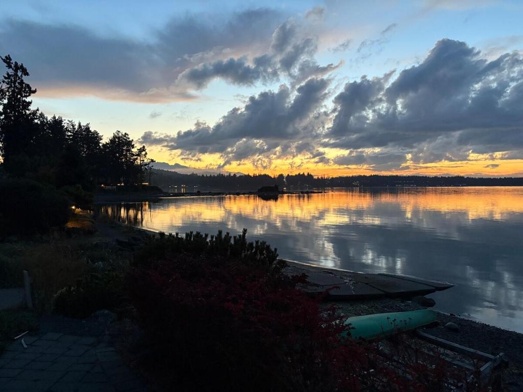 a sunset over a lake with a boat on it at Oceanside Getaway in Nanoose Bay