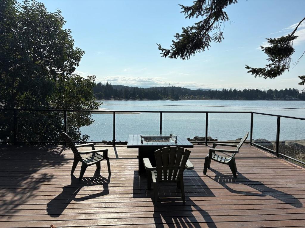 a table and two chairs on a deck with a view of a lake at Oceanside Getaway in Nanoose Bay