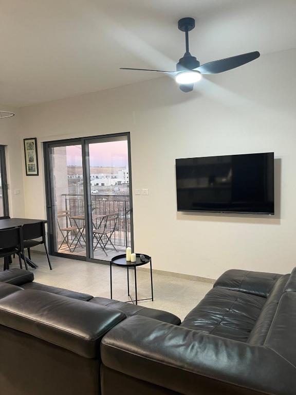 a living room with a couch and a flat screen tv at צימר בלב הגולן קצרין in Qasrîne