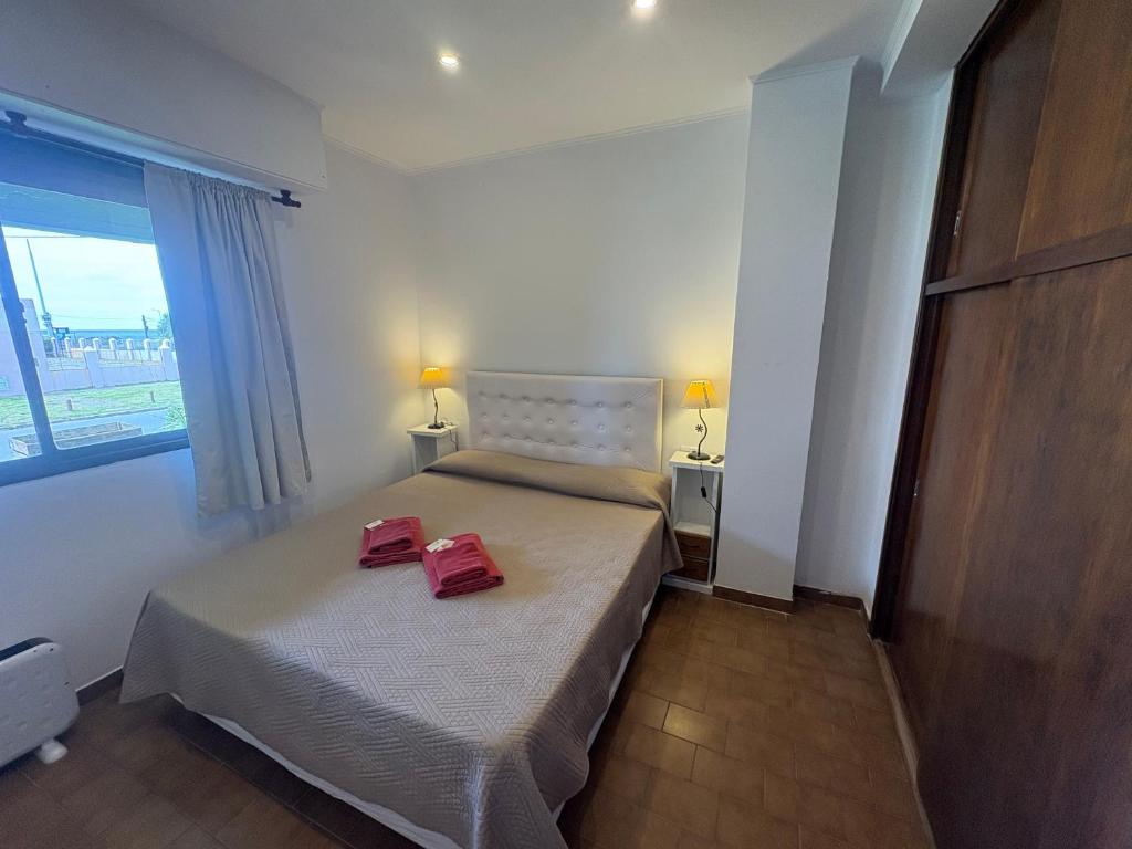 Un dormitorio con una cama con dos zapatos rojos encima. en Rincon del Oceano, en Santa Teresita
