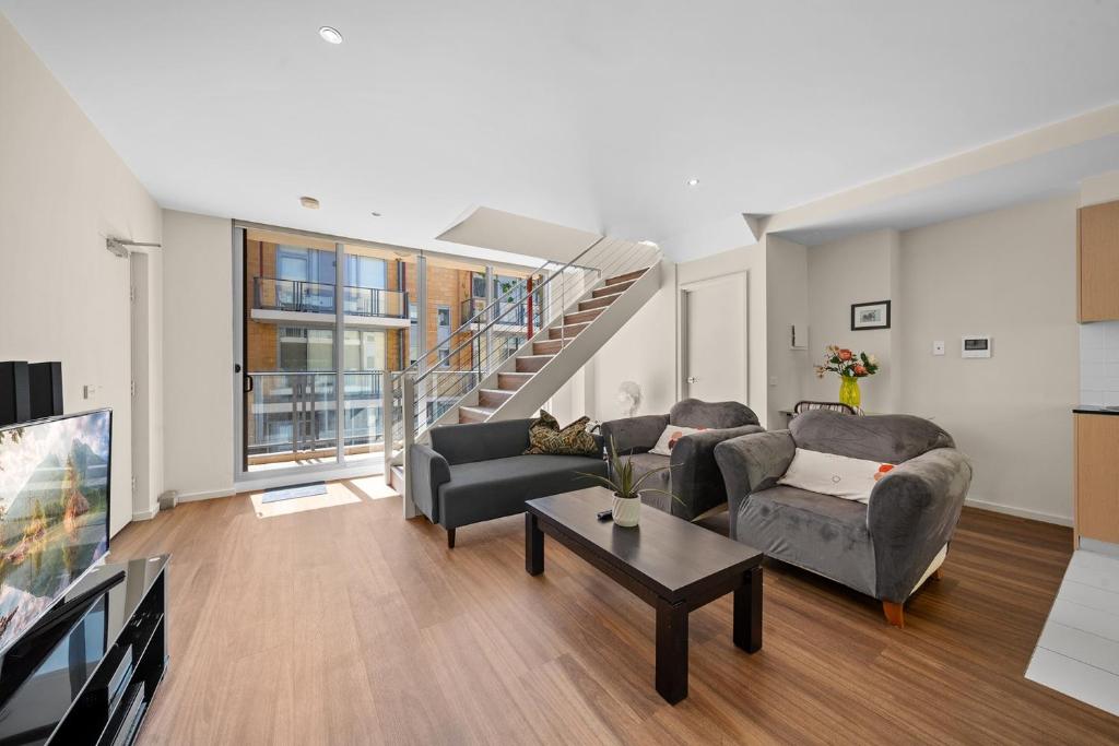 キャンベラにあるSpacious Apartment with Gym & Pool Accessのソファ2つと階段のあるリビングルーム