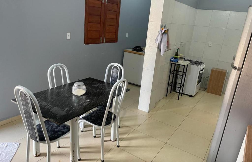 Una mesa de comedor con sillas y una cocina. en Charcara JJC, en Arapiraca
