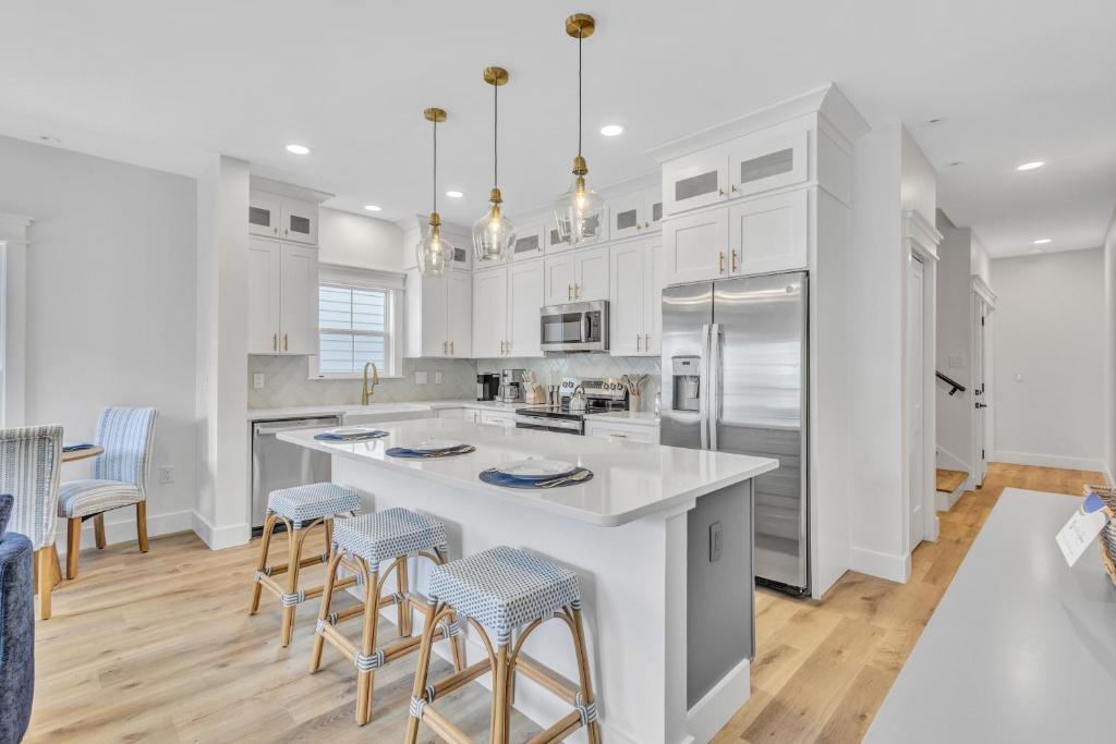 une cuisine avec des placards blancs et un grand îlot avec des tabourets de bar dans l'établissement 200 Olive Shell Court, à Île de Hilton-Head