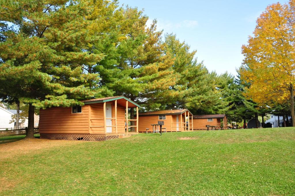 a cabin in a park with trees and grass at Plymouth Rock Camping Resort One-Bedroom Cabin 6 in Elkhart Lake