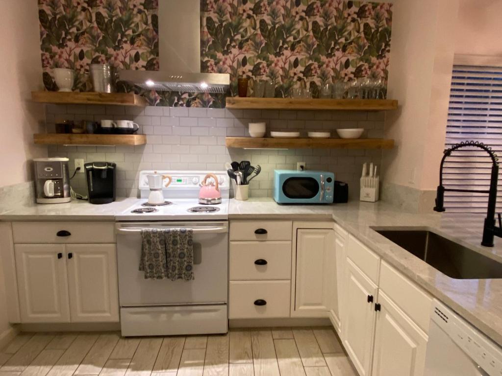 cocina con armarios blancos, fogones y fregadero en Relaxing beach getaway just steps to the shore, en Coquina Gables