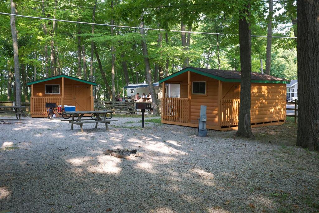 a park with two lodges and a picnic table at Plymouth Rock Camping Resort Studio Cabin 2 in Elkhart Lake