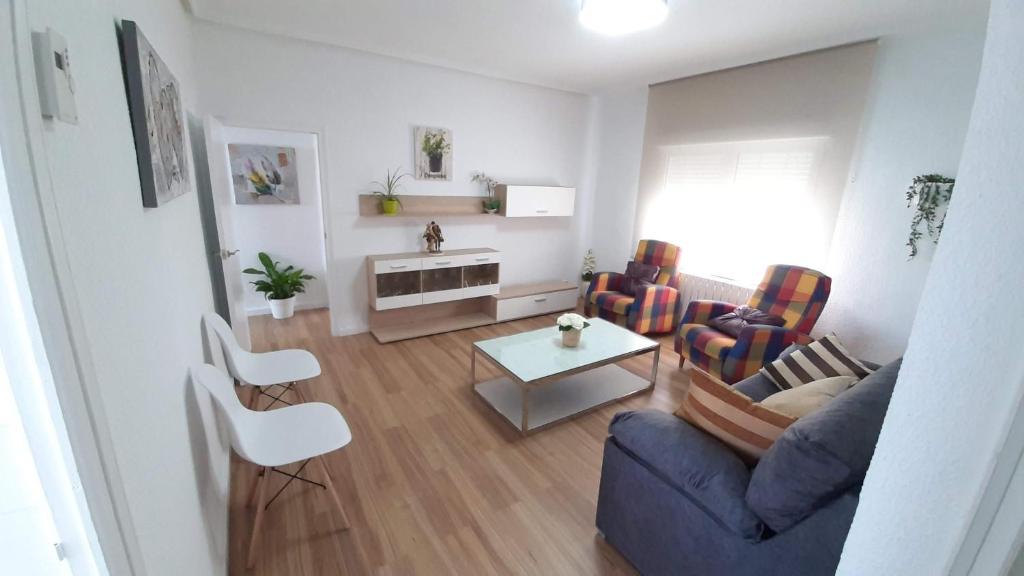 ein Wohnzimmer mit einem blauen Sofa und Stühlen in der Unterkunft Apartamento San Juan in Casas-Ibáñez