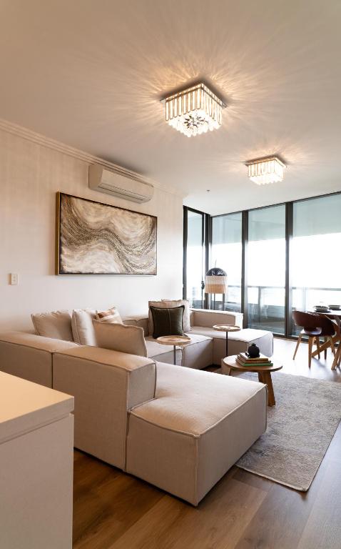 a living room with white furniture and large windows at Stadium Retreat in Sydney