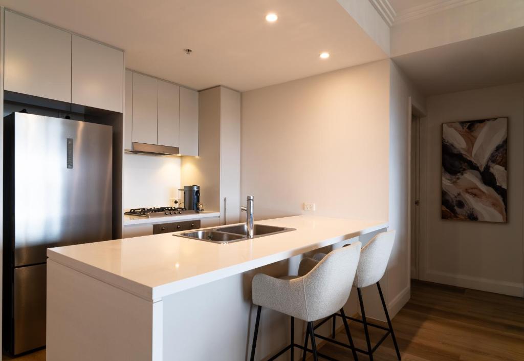 een witte keuken met een wastafel en een koelkast bij Stadium Retreat in Sydney
