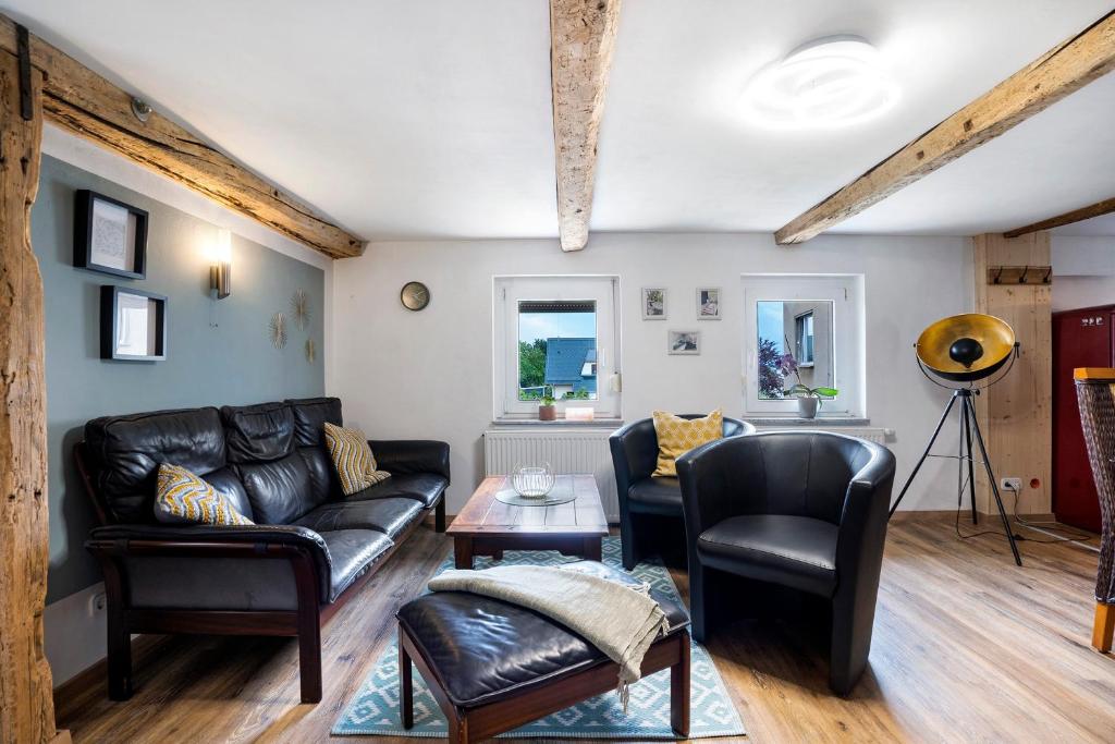 a living room with a black leather couch and chairs at Wünsch Dir was in Großweitzschen