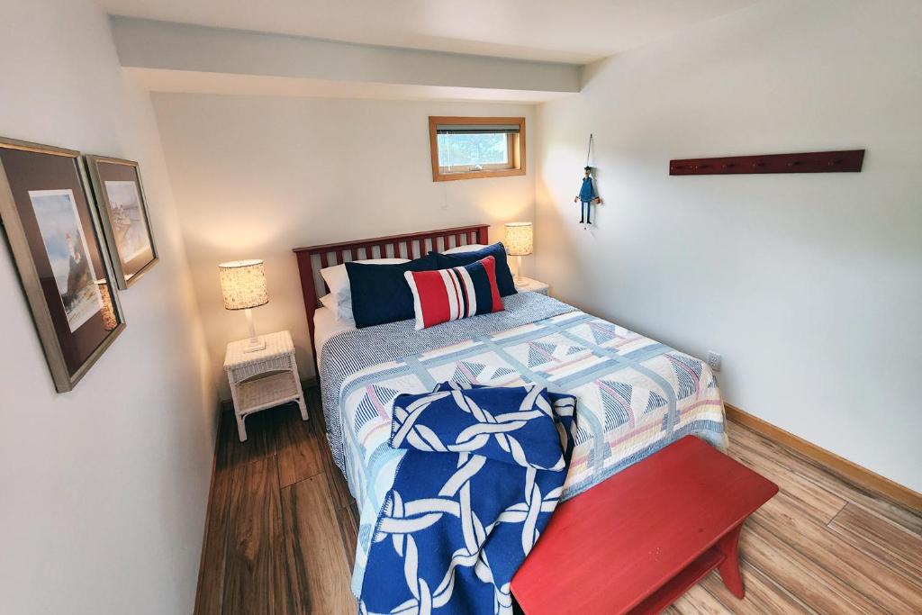 a small bedroom with a bed and a red bench at Walk to Everything! Hot Tub! Shorepine Haven in Yachats
