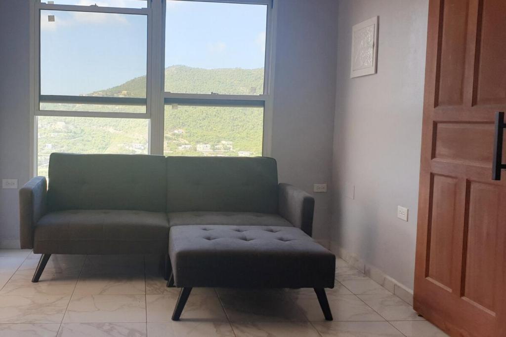 a living room with a couch and a stool and a window at Nos Soño in Upper Prince's Quarter
