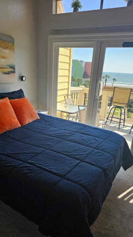 a bedroom with a blue bed and a view of the ocean at The Oceanfront Galveston Apartments in Galveston