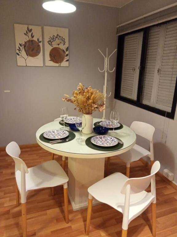 a white dining room table with white chairs and a table with plates at Cozy apartment in Mendoza
