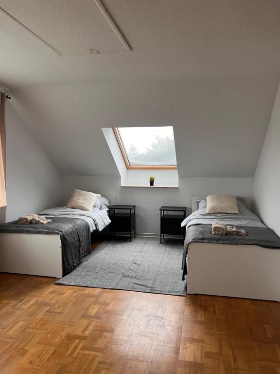 Un dormitorio abuhardillado con dos camas y una ventana. en A6 Aparts, en Garbsen