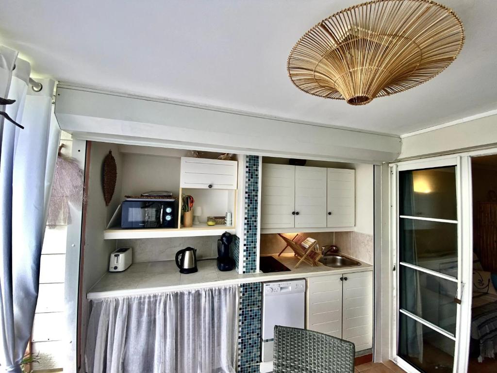eine Küche mit weißen Schränken und einer Decke in der Unterkunft Studio Céladon village vacances Ste Anne Guadeloupe in Sainte-Anne
